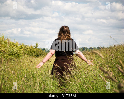 Frau allein zu Fuß unter langen Gräsern in einem Feld in East Yorkshire England UK Stockfoto