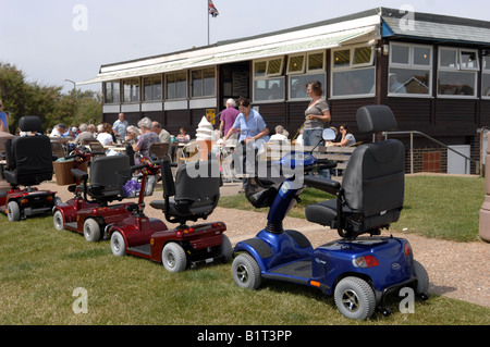 Mobilitätsroller, die hauptsächlich von OAPs verwendet werden, die vor einem Café in der Nähe von Worthing Sussex in Großbritannien geparkt sind Stockfoto