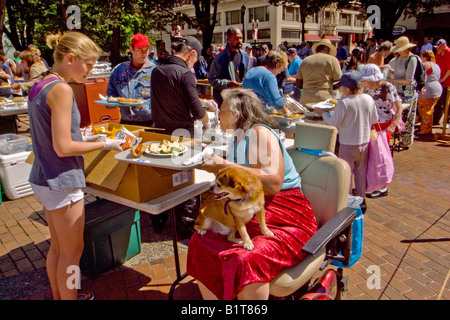 Tragen ihren Hund auf dem Schoß schließt sich eine Rollstuhl gebundene Frau andere Obdachlose für einen freien Sonntag Mahlzeit in Portland, Oregon Stockfoto