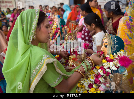 Eine Rajasthani-Frau macht eine Blume Offerting Shivas Gattin PARVATI auf dem GANGUR FESTIVAL UDAIPUR RAJASTHAN Indien Stockfoto