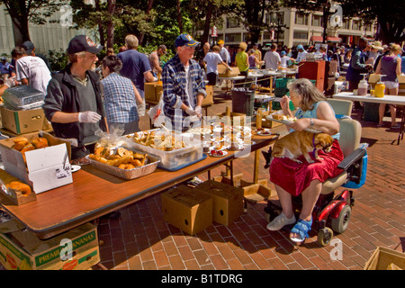 Tragen ihren Hund auf dem Schoß schließt sich eine Rollstuhl gebundene Frau andere Obdachlose für einen freien Sonntag Mahlzeit in Portland, Oregon Stockfoto
