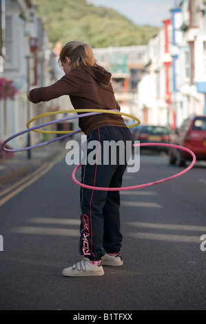 Teenager-Mädchen spielen mit Hula-Hoop Hoolah auf der Straße vor ihrem Haus Stockfoto