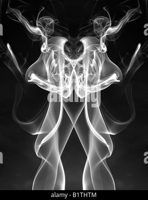Weißer Rauch Muster aus einem brennenden Räucherstäbchen.  Es wurde kopiert und gespiegelt, um eine organische Form zu bilden. Stockfoto