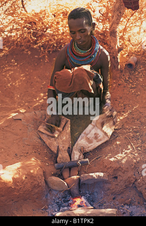 Samburu Frau arbeitet Ziegenleder Blasebalg Luft in das Kohlenfeuer für Ehemann Schmied nördlichen Kenia in Ostafrika Stockfoto