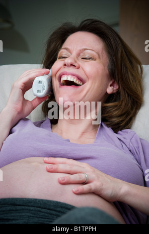 Schwangere Frau auf einem Stuhl sitzen und reden am Telefon Modell veröffentlicht Stockfoto