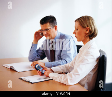 Mann und Frau mit Handy bei Geschäftstreffen Stockfoto