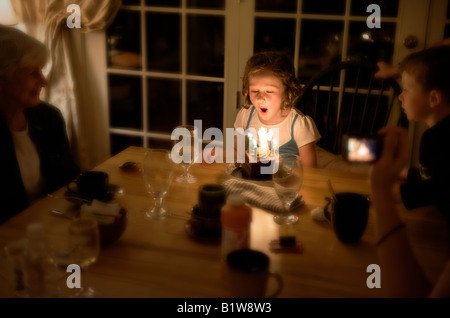 Sieben Jahre altes Mädchen bläst die Kerzen auf ihrem Geburtstagskuchen Stockfoto