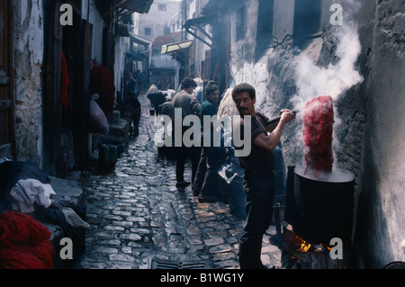 Marokko in Nordafrika Fez Street in der Wolle färben Souk mit Mann im Vordergrund heben Knäuel Garn von der Mehrwertsteuer des Farbstoffes dämpfen. Stockfoto