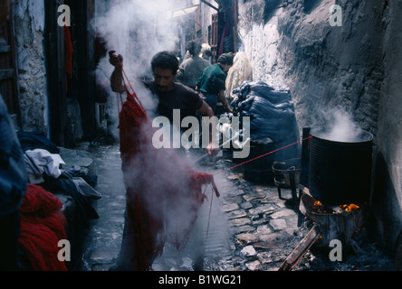 Marokko in Nordafrika Fez Street in der Wolle färben Souk mit Mann im Vordergrund heben Knäuel Garn von der Mehrwertsteuer des Farbstoffes dämpfen. Stockfoto