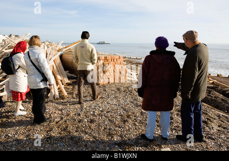 ENGLAND West Sussex Worthing fünf Leute betrachten Holz Rückstand am Strand von Schiffbrüchigen Eisprinzessin mit entfernten Pier Stockfoto