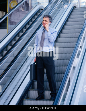 Mann am Handy auf Rolltreppe Stockfoto