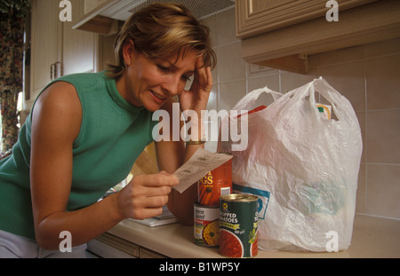 Frau verzweifelt ihr Einkaufen Auspacken und auf der Suche über Preise Stockfoto