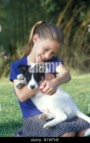 kleine Mädchen spielen mit einem Welpen im Garten Stockfoto