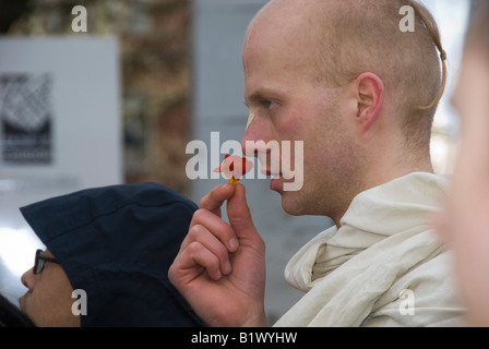 Hare-Krishna-Anhänger riecht Blüte während Leicester Square Guara Purnima Zeremonie von Lord Caitanya Stockfoto