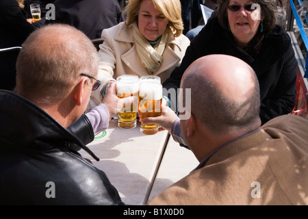 Zwei Paare Toast mit einem Bier an Straße Restauranttisch im Marktplatz in Delft. Niederlande. Stockfoto