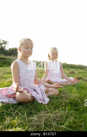 Porträt von zwei Freundinnen praktizieren Yoga im Sommer, Outdoor-Lotus-Sitz Stockfoto