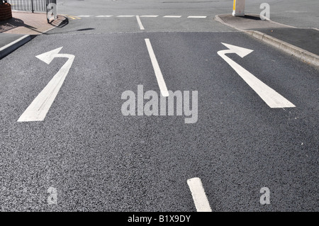 Konzept Wahl Entscheidung Änderung der Richtung Mitte der Straße Entscheidungen weiße Asphalt Pfeile links und rechts abbiegen geradeaus auf dem schwarzen Asphalt England Großbritannien Stockfoto