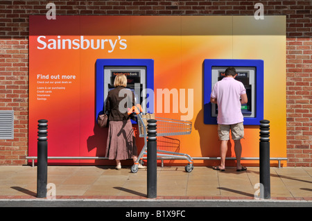 Sainsburys Supermarkt Loch in Wand Geldautomaten und Benutzer Stockfoto