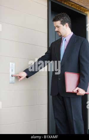 Geschäftsmann durch Betätigen der Taste für Aufzug in einem Bürogebäude Stockfoto