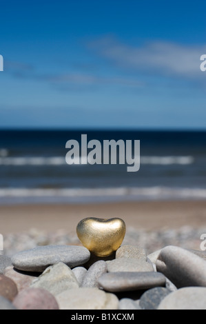 Goldenes Herz geformte Kiesel auf die Kieselsteine am Strand von Findhorn, Schottland Stockfoto