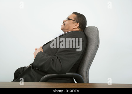 Seitenansicht eines Geschäftsmannes in einem Bürostuhl zu sitzen und denken Stockfoto
