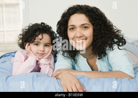 Porträt einer Mitte Erwachsene Frau mit ihrer Tochter auf dem Bett liegend Stockfoto