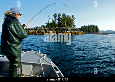 Frau spielt einen silbernen Coho Lachs Fisch auf knorrige Insel im Norden von British Columbia Stockfoto