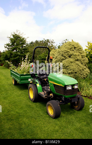 JOHN DEERE 4010 ZUGMASCHINE UND ANHÄNGER IN EINEM GARTEN ARBEITEN. Stockfoto