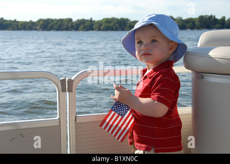 Ein Kleinkind junge hält eine amerikanische Flagge auf einem Boot in die Fourth Of July. Stockfoto