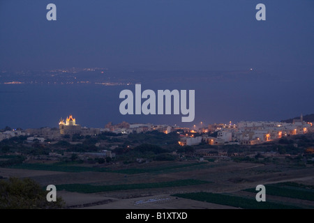 Das Dorf Ghajnsielem, Gozo, von Nadur Höhen gesehen. Im Norden von Malta ist über den Kanal sichtbar. Stockfoto