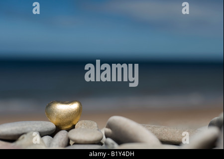 Goldenes Herz geformte Kiesel auf die Kieselsteine am Strand von Findhorn, Schottland Stockfoto