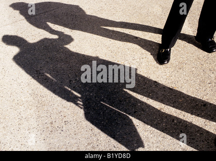 Schatten auf dem Bürgersteig oder Bürgersteig. Zwei Geschäftsleute stehen und reden, treffen sich auf der Straße und geben sich im Zeichen der Freundschaft die Hände. Stockfoto