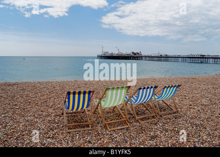 Leere Liegestühle am Strand von Brighton mit Pier im Hintergrund Stockfoto