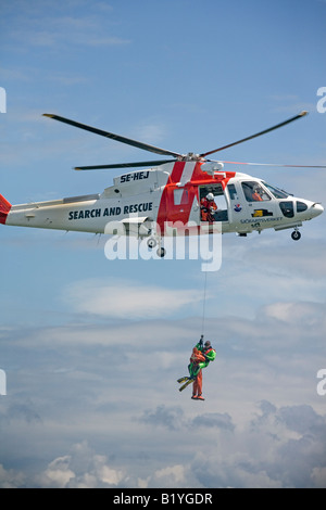 Such- und Rettungsdienst SAR-Hubschrauber-Team hisst eine Person mit Hilfe der Rettungsschwimmer Stockfoto