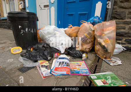 Kunststoff-Müll Taschen verstreut und zerrissenen offen auf der Straße, deren Inhalt auf dem Bürgersteig, Aberystwyth Wales UK verschütten Stockfoto