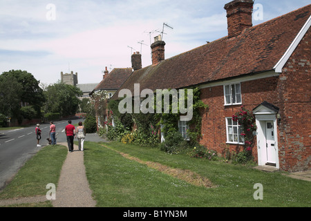 Zwei Frauen chatten auf der Straße und ein paar Fuss mit Kirche und hübschen Cottages Orford, Suffolk Stockfoto