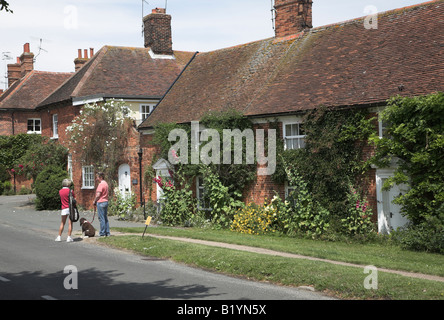 Zwei Frauen plaudern auf der Strasse mit Kirche und hübschen Cottages Orford, Suffolk Stockfoto