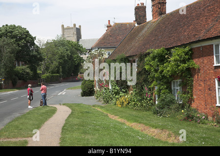 Zwei Frauen plaudern auf der Strasse mit Kirche und hübschen Cottages Orford, Suffolk Stockfoto