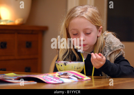 Lizenzfreie kostenlose Foto von jungen Mädchen essen ihren Frühstückstee beim Lesen einer Zeitschrift zu Hause am Wochenende UK Stockfoto