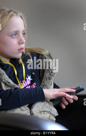 Foto von junge Mädchen beobachten tv oder dvd mit Fernbedienung in Familie nach Hause UK Stockfoto