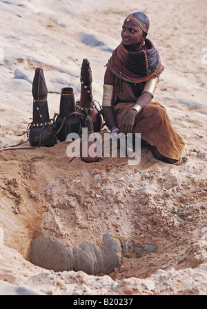 Samburu Frau kauert über den Brunnen mit ihren Kalebassen füllen mit Wasser Nord Kenia in Ostafrika Stockfoto