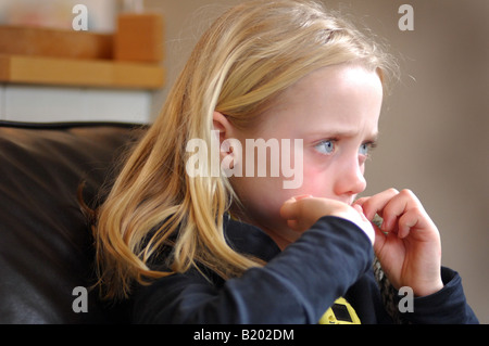 Foto des jungen Mädchens, tv oder dvd anschauen, während ihrer Nailsl in Familie beißen nach Hause UK Stockfoto