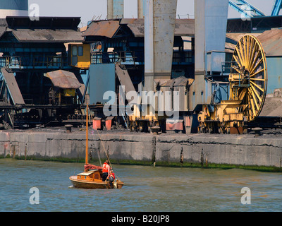 Kleines Vintage Holz Segelboot Yacht Segeln vorbei an riesigen Maschinen in der Hafenstadt Antwerpen Flandern Belgien Stockfoto