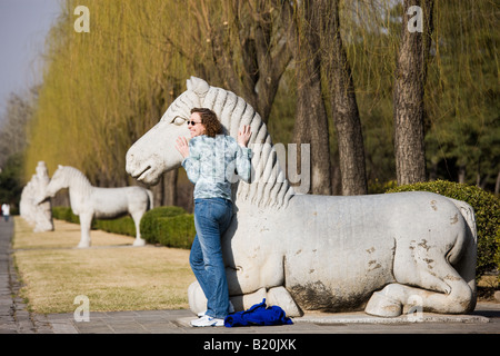 Touristischen posiert mit Statue von einem ruhenden Pferd Geist Weg Ming Gräber Changling Peking China Stockfoto