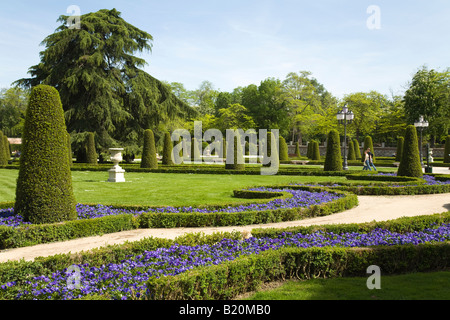 Spanien Madrid Menschen gehen auf Bürgersteig durch Gärten im Retiro Park Parque del Buen Retiro, geformte Sträucher und Blumen Stockfoto
