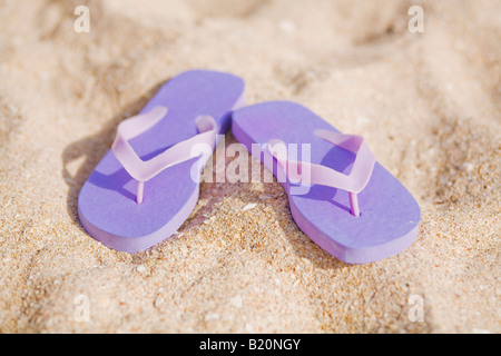 Lila Flip Flops in den Sand am Strand. Stockfoto