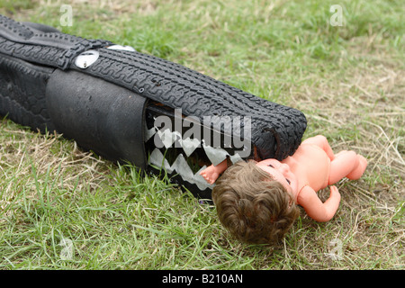 Kunst-Krokodil aus alten Autoreifen mit Kinder Spielzeug aus Plastik Puppe gemacht Stockfoto
