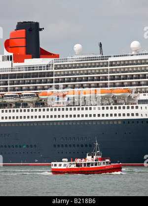 Die Hythe Fähre wird durch die große Cunard transatlantischen Liner Queen Mary 2 während in Southampton, Hampshire, England angedockt Schatten gestellt. Stockfoto