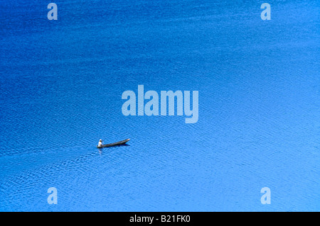 Ein einsamer einsame Mann in einem hölzernen Einbaum Kanu Springer-über Lake Bunyonyi. Stockfoto