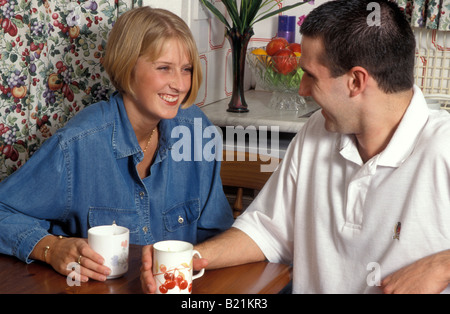 Junges Paar in der Küche plaudern über Becher Kaffee Stockfoto